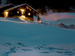 Gemütlich beleuchtetes Chalet in verschneiter Winterlandschaft – Symbol für wohlige Wärme und optimalen Schlafkomfort mit den saisonal passenden Duvets von billerbeck.