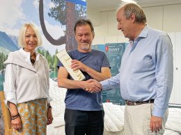 Peter Gygli mit Herrn Ermert und Frau Ermert. Peter Gygli hält das Jubiläumsgeschenk in der Hand.