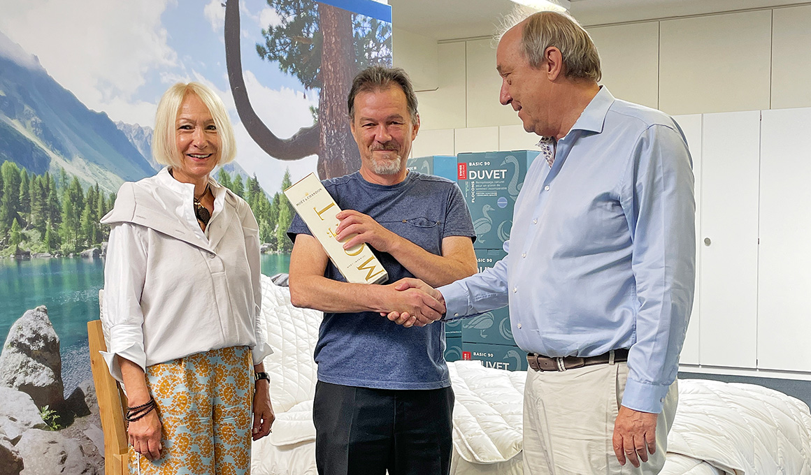 Peter Gygli mit Herrn Ermert und Frau Ermert. Peter Gygli hält das Jubiläumsgeschenk in der Hand.