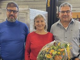 Giuseppe di Mariano, Heidi Göldi und Guido Stutz posieren für die Kamera. Heidi Göldi hält in ihrer linken Hand den Blumenstrauss für das Jubiläum.