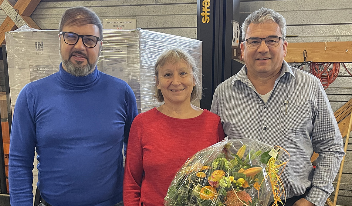 Giuseppe di Mariano, Heidi Göldi und Guido Stutz posieren für die Kamera. Heidi Göldi hält in ihrer linken Hand den Blumenstrauss für das Jubiläum.