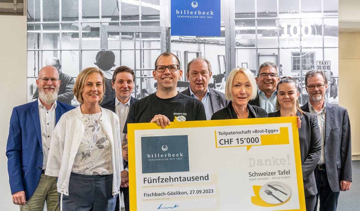 Billerbeck Mitarbeiter und ein Mitarbeiter der Schweizer Tafel posieren vor der Kamera. Der Mitarbeiter der Schweizer Tafel hält den Check in der Hand für das regionale Engagement von billerbeck.