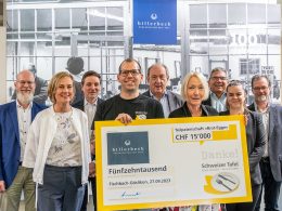 Billerbeck Mitarbeiter und ein Mitarbeiter der Schweizer Tafel posieren vor der Kamera. Der Mitarbeiter der Schweizer Tafel hält den Check in der Hand für das regionale Engagement von billerbeck.