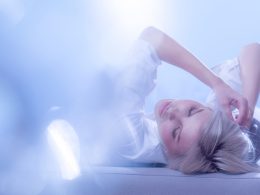 Frau liegt entspannt im Bett in traumhafter Lichtstimmung – Symbolbild für die Geheimnisse des Schlafs und die nächtlichen Regenerationsprozesse des Körpers.