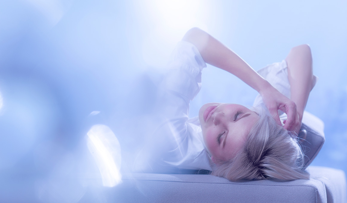 Frau liegt entspannt im Bett in traumhafter Lichtstimmung – Symbolbild für die Geheimnisse des Schlafs und die nächtlichen Regenerationsprozesse des Körpers.