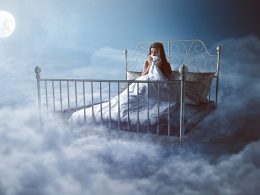 Mädchen sitzt nachdenklich in einem Bett über den Wolken bei Mondlicht – Symbolbild für bewussten Umgang mit Träumen, Traumdeutung und nächtliche Selbstreflexion.