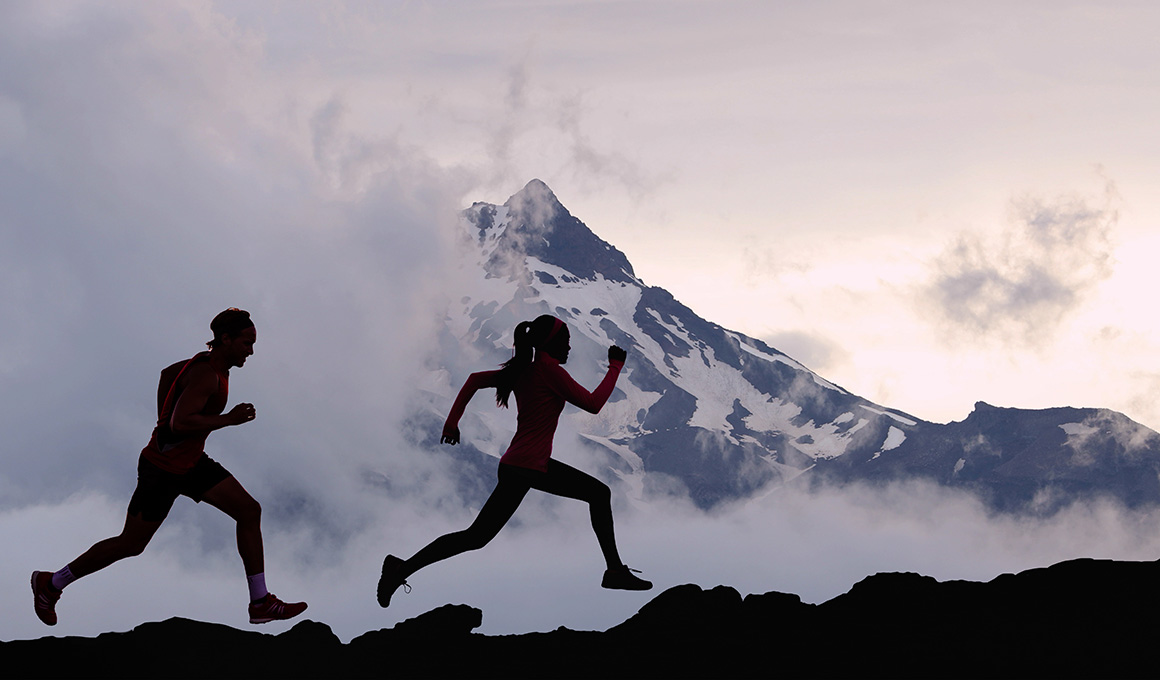 Zwei Menschen joggen in der Natur vor beeindruckender Bergkulisse – Symbol für den Kontrast zwischen analoger Bewegung im Freien und digitaler Schlafüberwachung im Alltag.