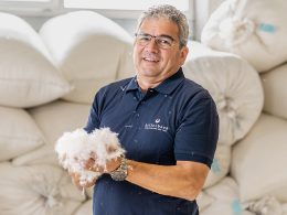 Guido Stutz posiert für die Kamera. Er hält weisse Gänsedaunen in den Händen.