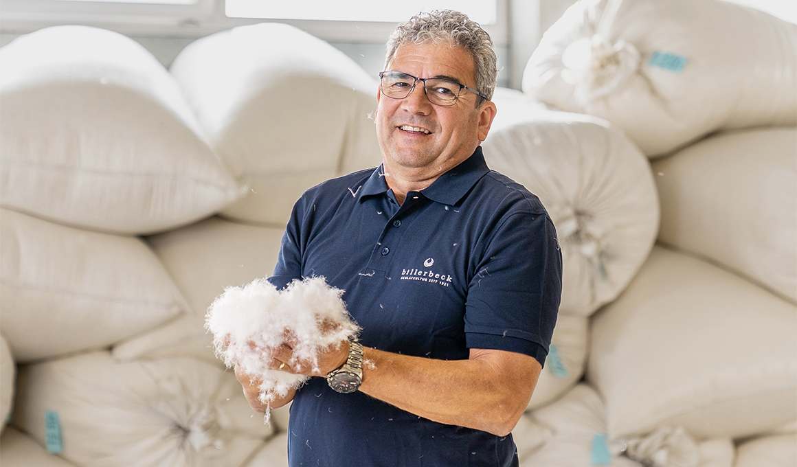 Guido Stutz posiert für die Kamera. Er hält weisse Gänsedaunen in den Händen.