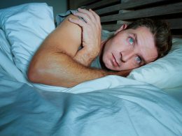 Mann liegt nachts wach im Bett und schaut nachdenklich – typisches Szenario für häufiges nächtliches Aufwachen und Schlafstörungen.