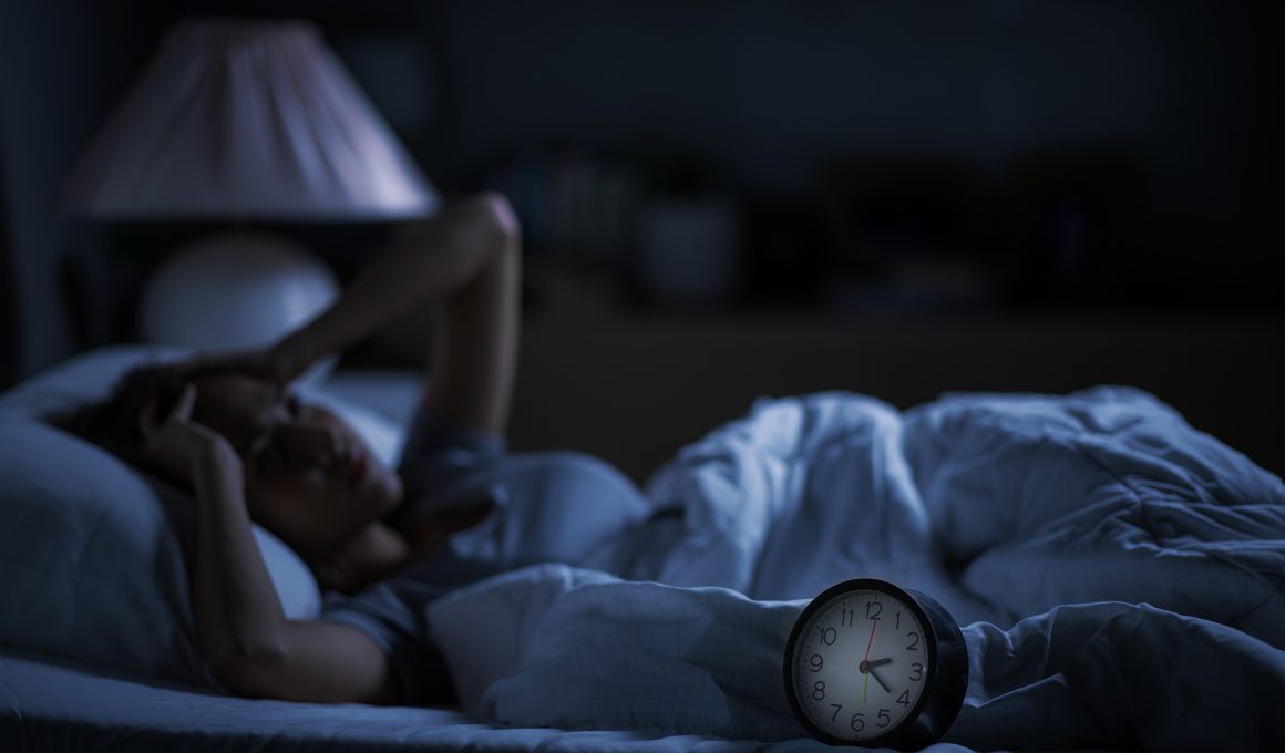 Frau liegt nachts wach im Bett.