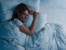 Schlafende Frau im Bett, die ein Kissen im Arm hält.